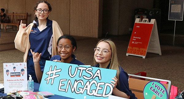 Students at an event holding a UTSA Engaged poster